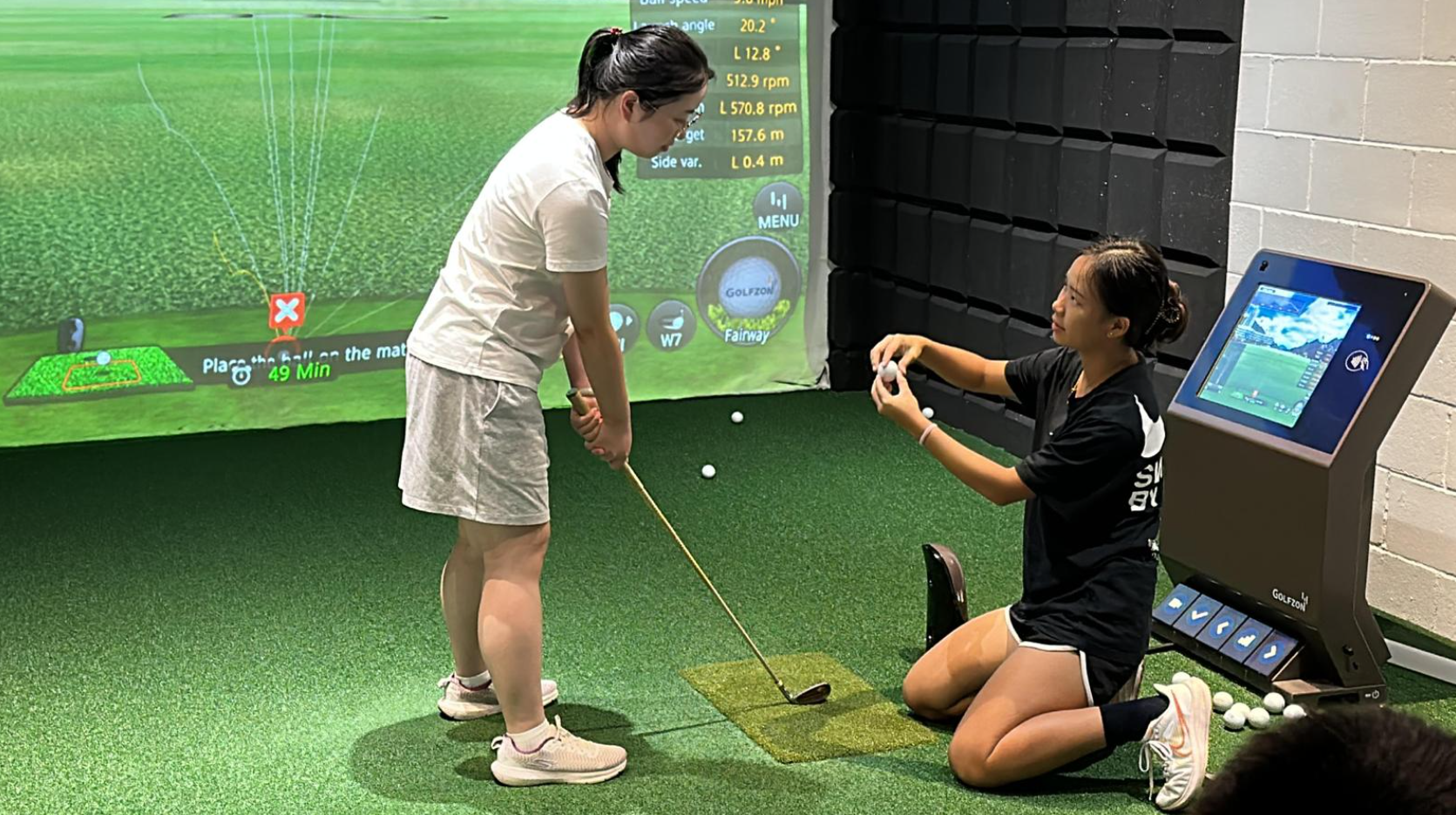 Tongyu (right) coaching a beneficiary at Tanjong Pagar Youth Network Urban Indoor Golfer event (2023).