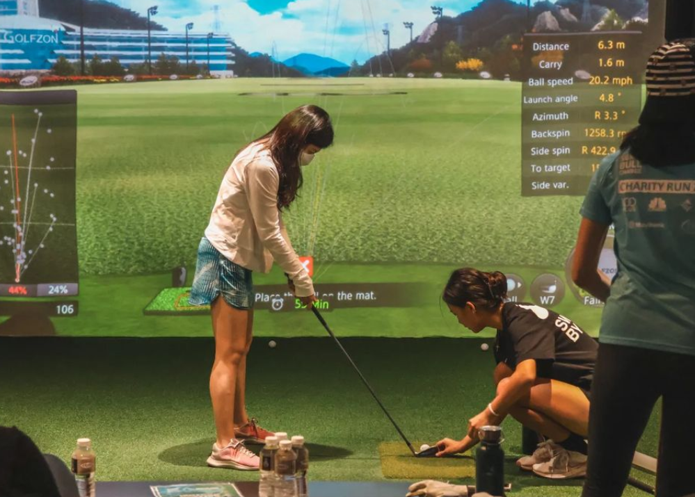 Tongyu (right) coaching a beneficiary at Tanjong Pagar Youth Network Urban Indoor Golfer event (2023).